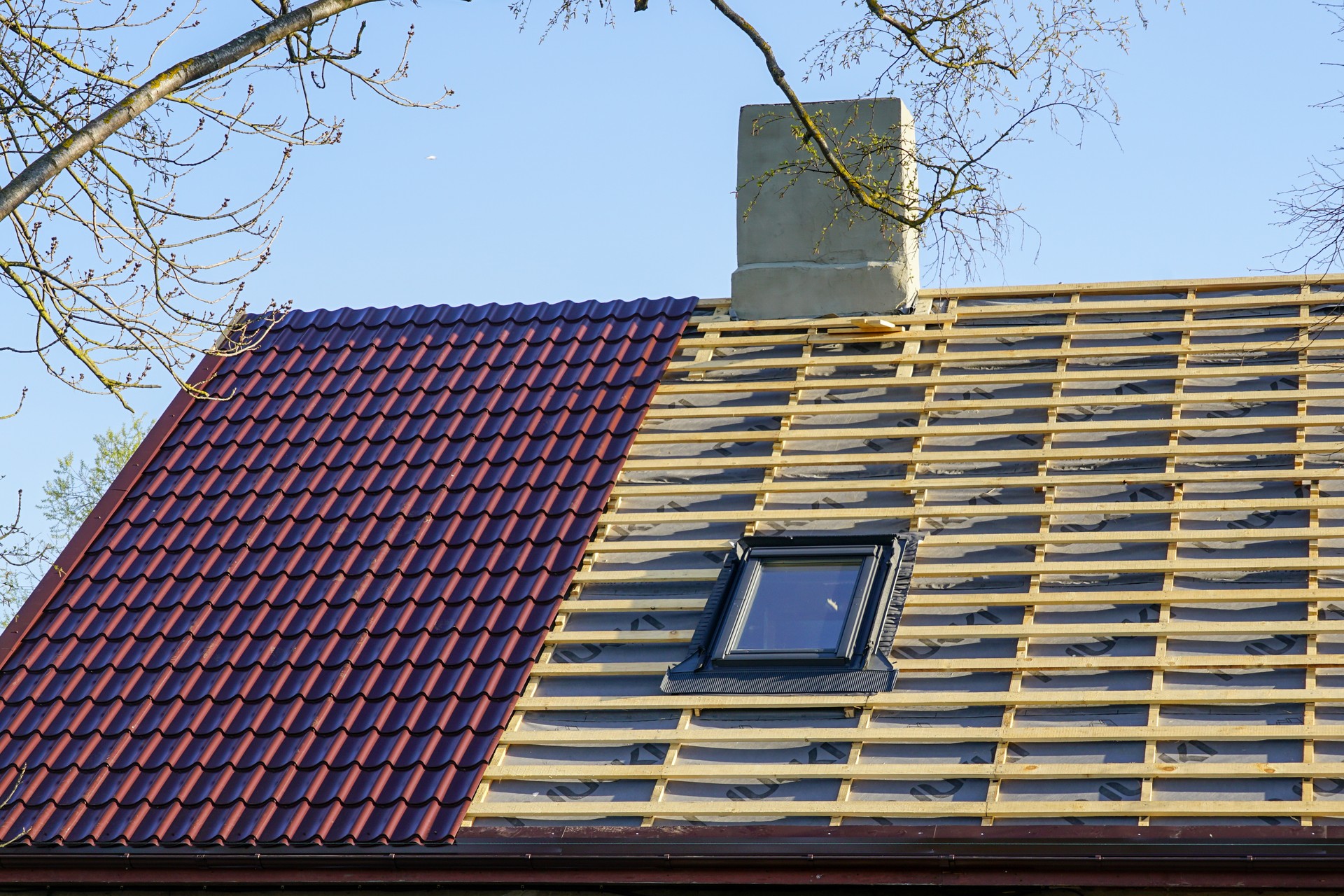 Replacement the roof covering of a small private house, half replaced, half not yet, metal roofing